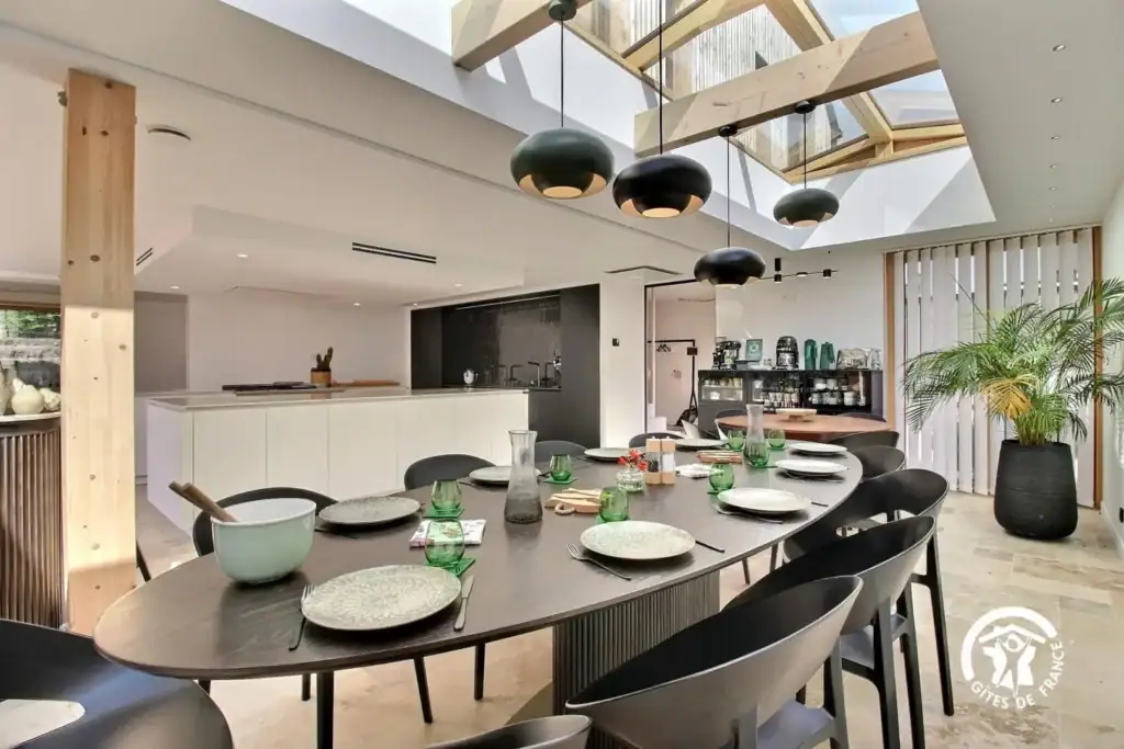 Salle à manger élégante avec grande table, vaisselle et décoration contemporaine.